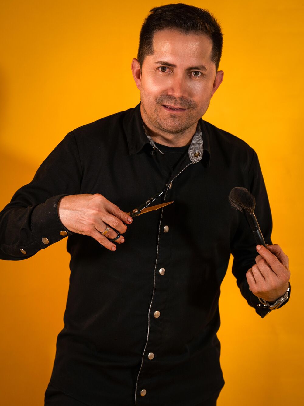 Jheison, colorista de Jheison Hair Lab, con tijeras y peine en la mano